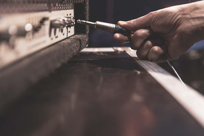 A hand plugs in a stereo audio cable into an amplifier in this file photo. Learn about implementing new audio visual technologies into your business at CenturyAV.com.